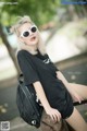 A woman wearing a black shirt and sunglasses sitting on a bench.