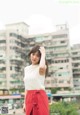 A woman in a white top and red skirt posing for a picture.