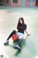 A woman sitting on a basketball court holding a basketball.