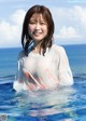 A woman in a white shirt standing in the ocean.