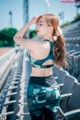 A woman in a sports bra top and leggings standing in a stadium.