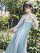 A woman in a blue and white dress standing in a garden.