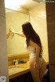 A woman in a white lingerie standing in front of a mirror.